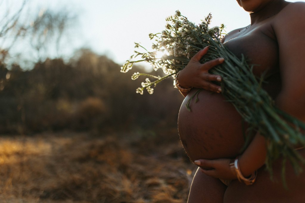 pregnant tummy, with flowers, golden light behind