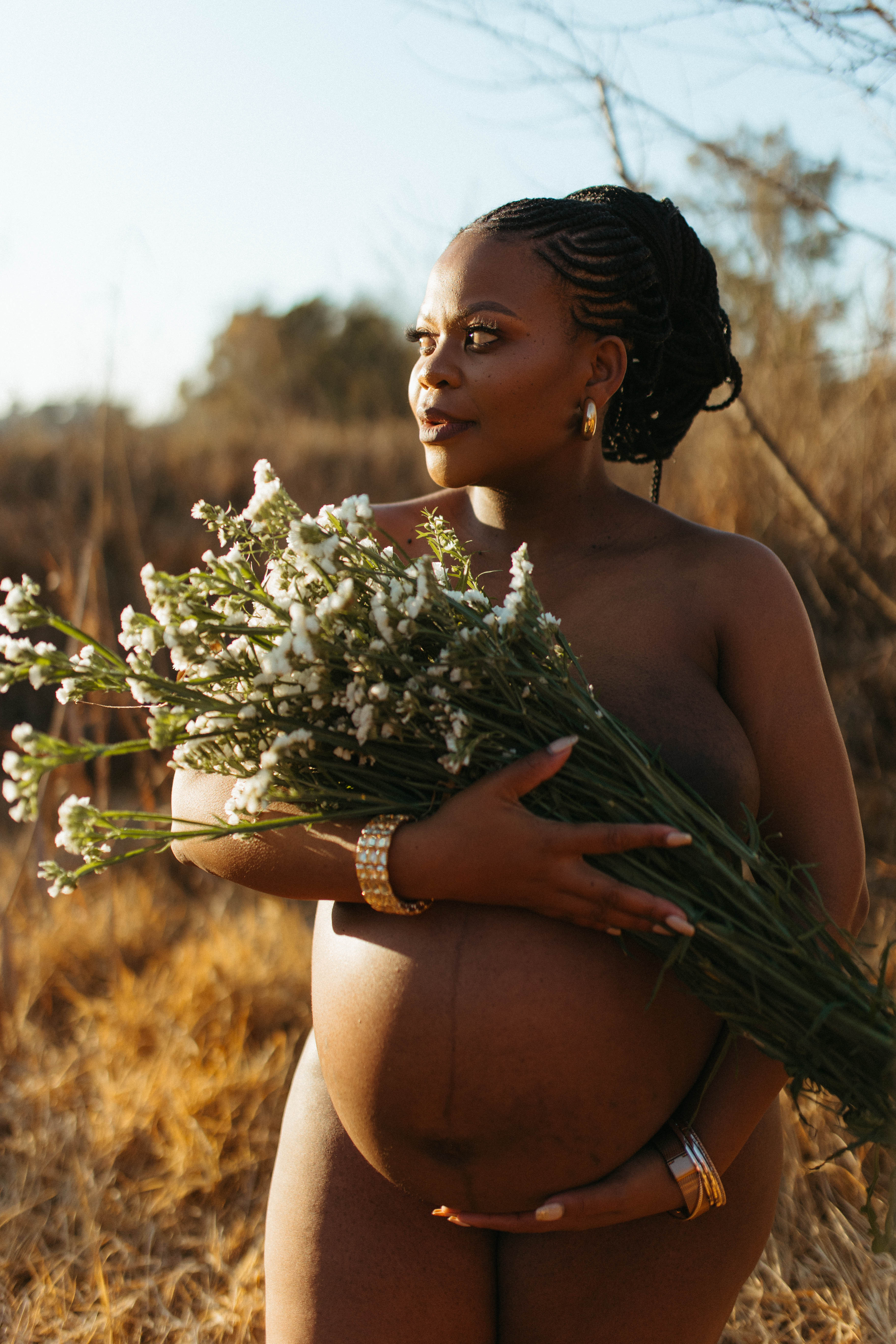 beautiful pregnant mama to be holding flowers over her breasts