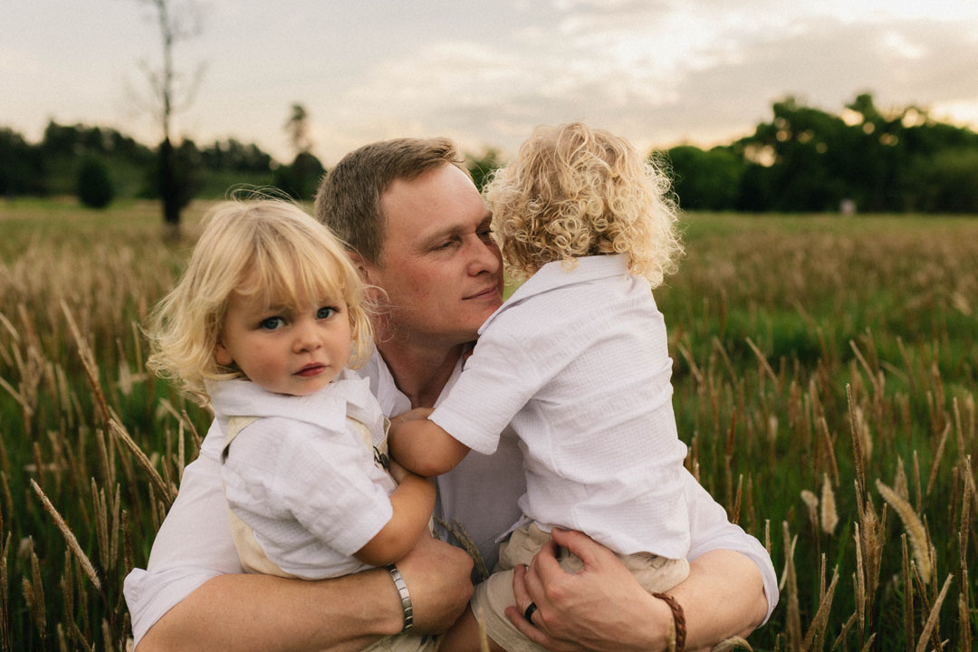 Father playing with baby whilst mother watches during lifestyle family session