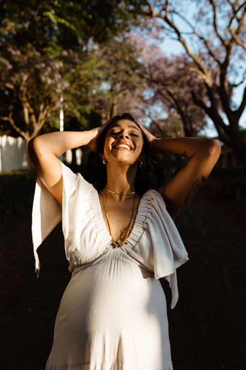 Joyful pregnant mother during golden hour maternity photoshoot under jacaranda trees Johannesburg