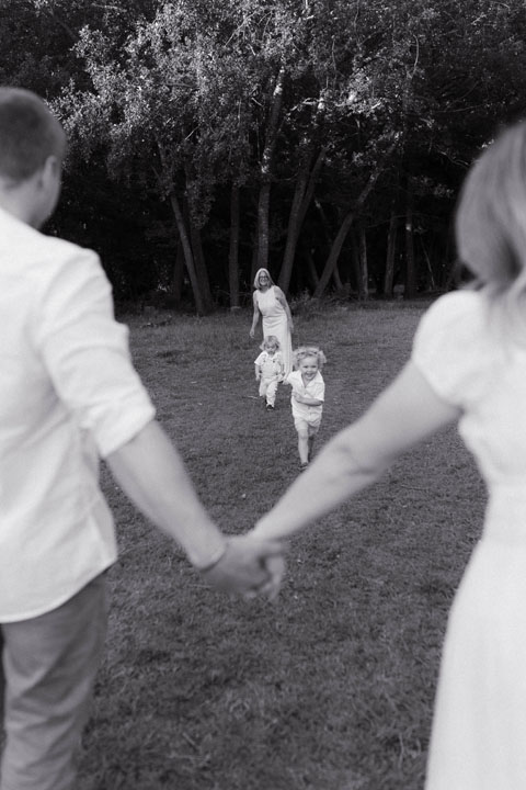 Toddler running towards parents during candid family photoshoot golden hour